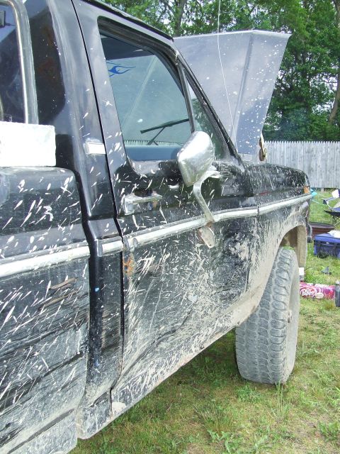 1986 Ford Bronco - This black pickup truck is heavily covered in mud, obscuring its original appearance.