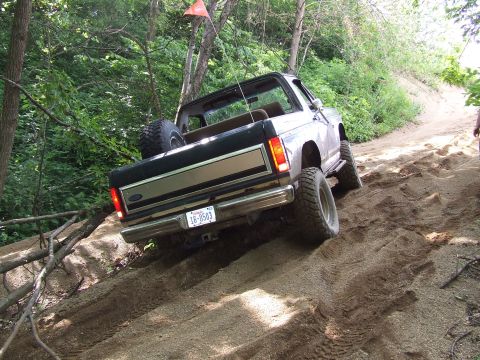 1986 Ford Bronco - This 1986 Ford Bronco is shown navigating a steep, sandy incline with a spare tire mounted on the rear.