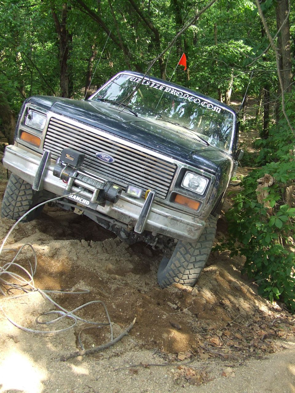 Dark blue 1986 Ford Bronco off-roading on a dirt trail