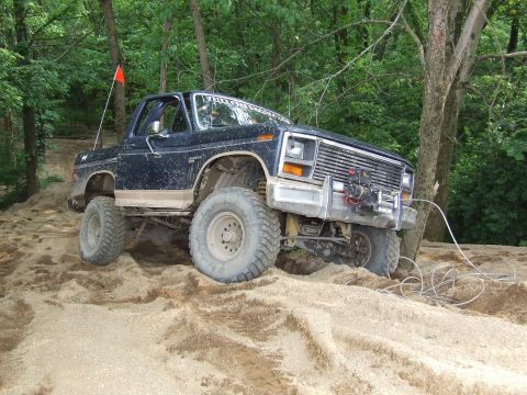 1986 Ford Bronco - This lifted Ford Bronco navigates a sandy incline with a winch attached to its front bumper.