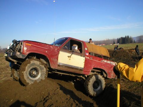 1978 Ford Bronco - Red and white 1978 Ford Bronco modified for off-road use, climbing a dirt embankment.