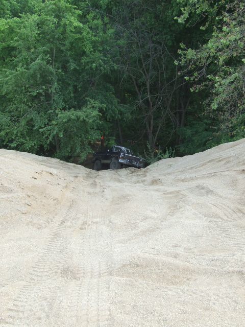 1986 Ford Bronco - Pickup truck navigates a steep sandy incline surrounded by dense foliage.