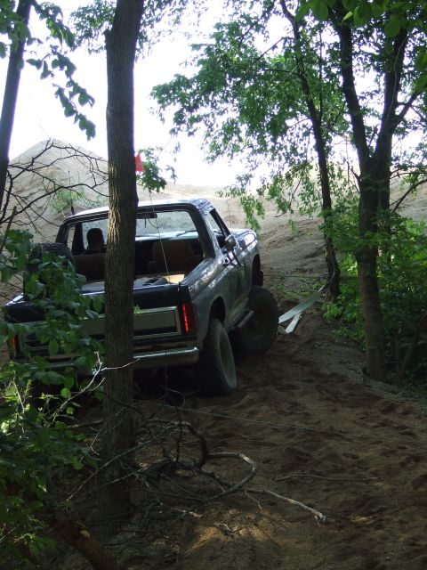 1986 Ford Bronco - This vehicle is navigating a steep, sandy incline surrounded by dense foliage.