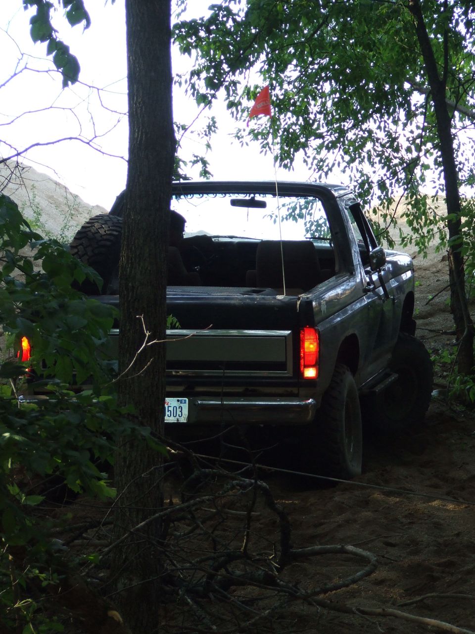Rear view of a 1986 Ford Bronco off-roading, with a spare tire visible