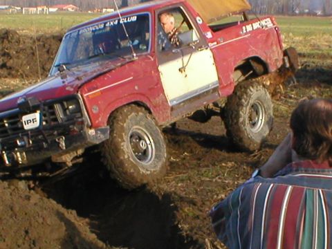 1978 Ford Bronco - 1978 Ford Bronco navigating a muddy off-road course, driver visible.