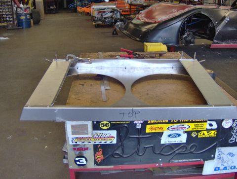 1978 Ford Bronco - A custom metal shroud, likely for a radiator, sits on a workbench with stickers on its base.