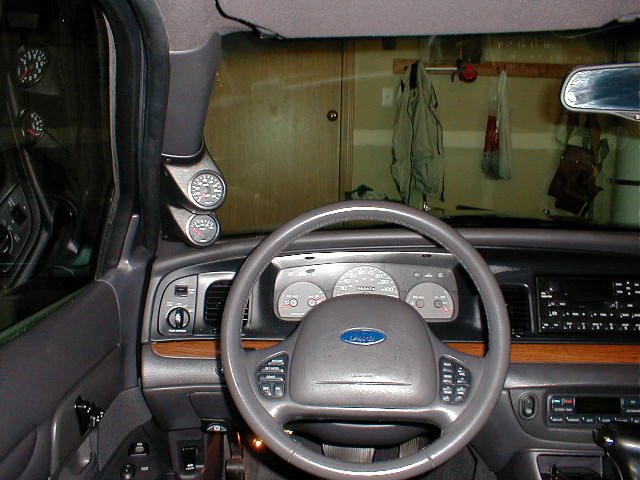 2002 Ford Crown Victoria interior showing dashboard, steering wheel, and aftermarket gauges