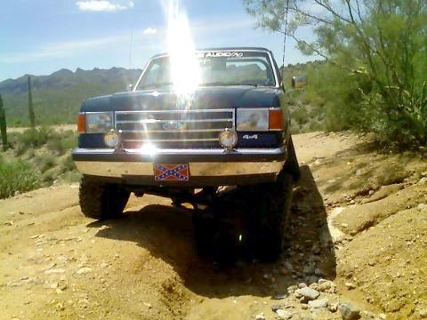 1991 Ford Bronco - A 1991 Ford Bronco is shown off-road, a rebel flag sticker on its front bumper.