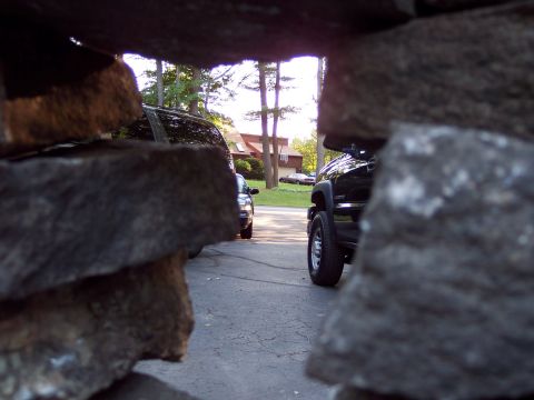 2001 Ford Crown Victoria - A view of two parked black vehicles, one in the foreground and another further back, framed by rocks.