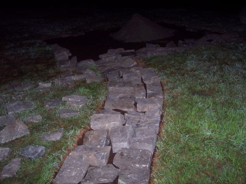 2001 Ford Crown Victoria - A stone wall is being constructed in a grassy area at night, with a pile of dirt in the background.