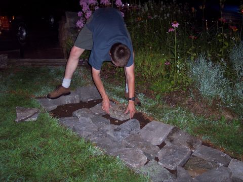 2001 Ford Crown Victoria - A person is carefully arranging stones to create a garden pathway.