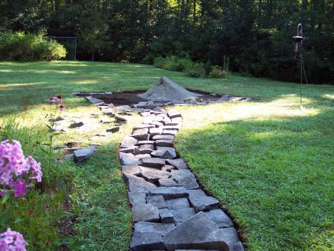 2001 Ford Crown Victoria - A stone pathway winds through a grassy yard, leading to a landscaping project with a pile of sand and gravel.
