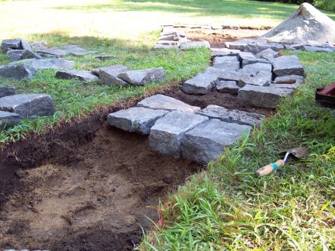 2001 Ford Crown Victoria - Outdoor construction project underway, large stones being placed for a patio and a gardening trowel resting on the grass.