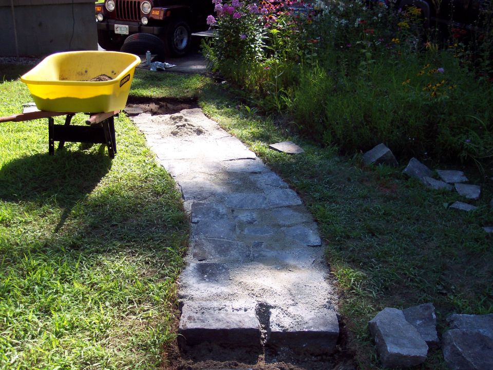 Brown Jeep Wrangler parked near a garden path under construction