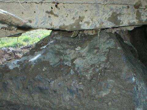 1978 Ford Bronco - Vehicle undercarriage seen from below, resting on a large rock.