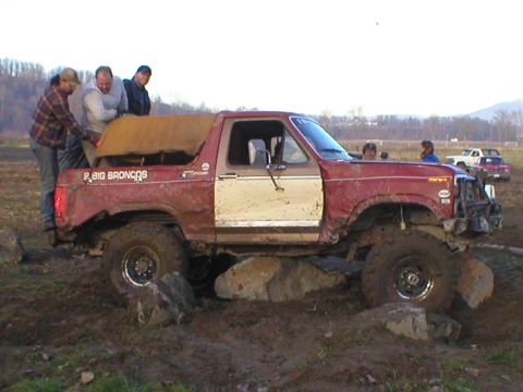 1978 Ford Bronco - This modified Ford Bronco is stuck on rocks while off-roading. Other vehicles are visible in the background.