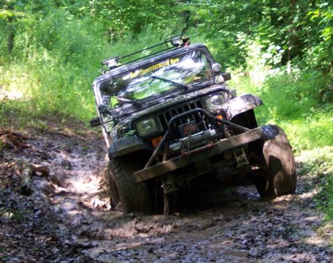 1978 Ford Bronco - This Jeep Wrangler is navigating a muddy off-road trail, with its front tires deep in the muck.
