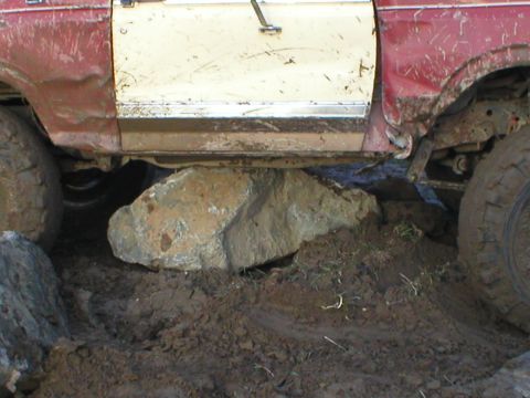 1978 Ford Bronco - A 1978 Ford Bronco is shown with a large rock lodged beneath its frame, indicating off-road use.