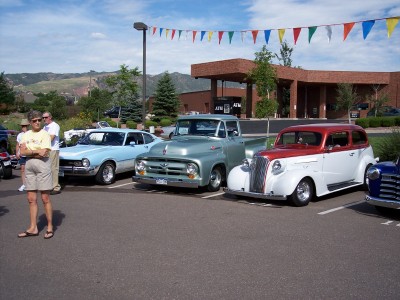 1972 Ford Ranchero - A collection of vintage vehicles are displayed in a parking lot under a string of colorful pennant flags.