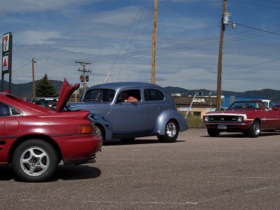 1972 Ford Ranchero - Three cars are parked in a lot on a sunny day.