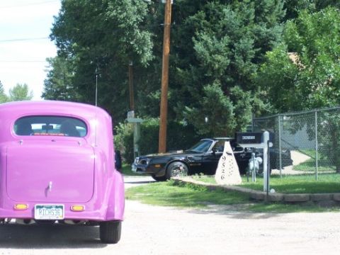 1972 Ford Ranchero - Two cars, a purple hot rod and a black 1977 Pontiac Trans Am, are parked in a driveway.