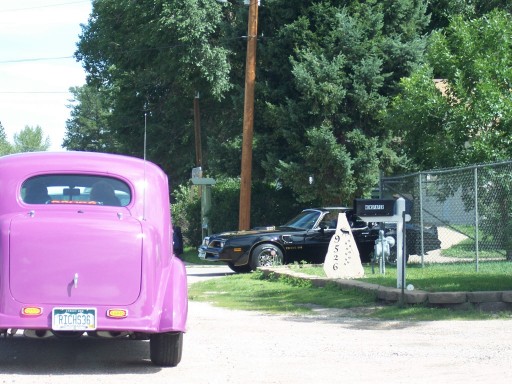 Purple hot rod parked in front of a black 1977 Pontiac Trans Am