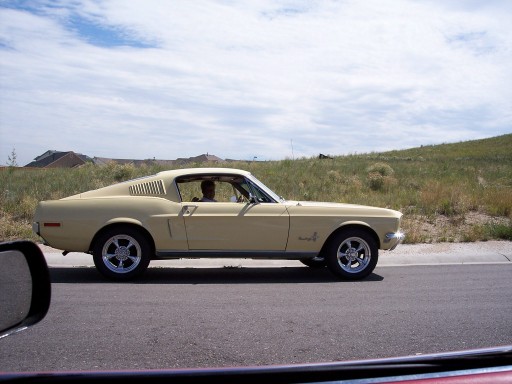 Pale yellow 1967 Ford Mustang Fastback driving on a road