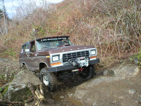 1978 Ford Bronco - A 1978 Ford Bronco navigates a challenging rocky trail, equipped with a winch for off-road recovery.