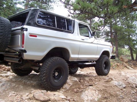 1978 Ford Bronco - A white 1978 Ford Bronco navigates a rocky trail, its off-road capabilities.