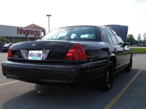 1998 Ford Crown Victoria - Rear view of a black 1998 Ford Crown Victoria with its hood open in a parking lot.