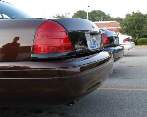 1998 Ford Crown Victoria - The rear of a brown 1998 Ford Crown Victoria is visible, parked next to other vehicles.