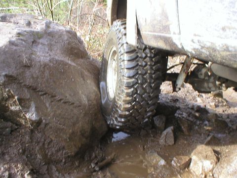 1978 Ford Bronco - Vehicle tire stuck on a rock during off-road driving.