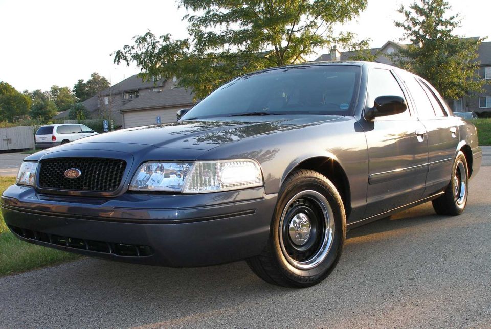 Dark gray Ford Crown Victoria sedan, front-left 3/4 view, on paved road