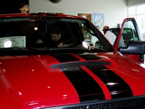 1972 Ford Ranchero - A red truck with black racing stripes is shown from the front, with text on the windshield reading 'ROUSH'.