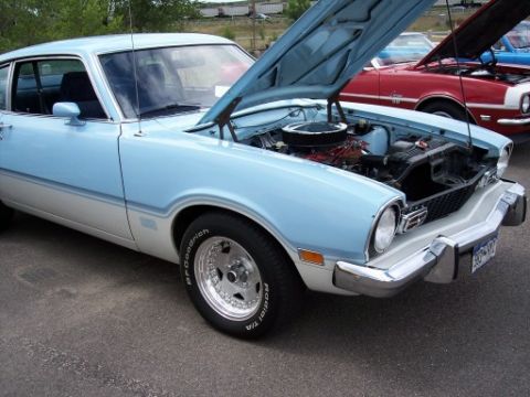 1972 Ford Ranchero - 1975 Ford Maverick with its hood open, parked next to another car with its hood up.