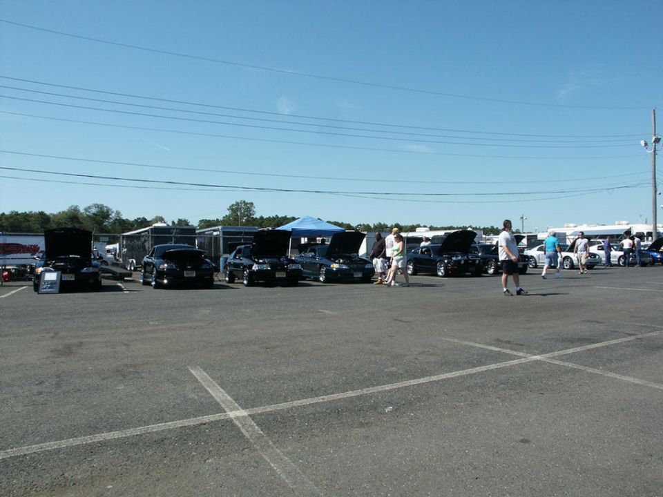 Cars with hoods up at a car show, some with trailers