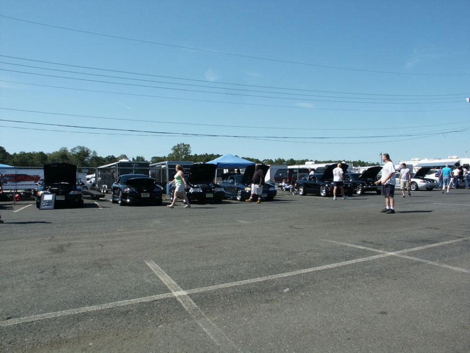 Outdoor car show with several cars parked and people milling around