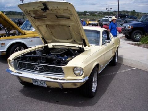 1972 Ford Ranchero - A classic yellow Ford Mustang is displayed with its hood up, alongside other vehicles at an outdoor event.