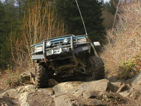 1978 Ford Bronco - This off-road vehicle navigates a challenging rocky path, its front end prominently displayed with a winch and brush guard.