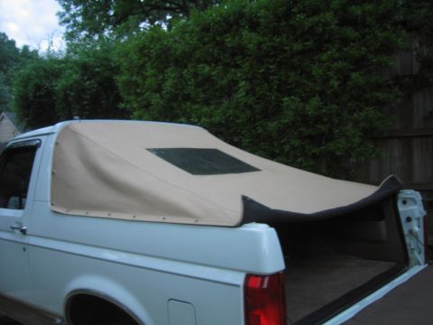 1996 Ford Bronco - Rear three-quarter view of a white full-size Ford Bronco fitted with a tan soft top in place of the fiberglass hardtop, the rear window sec…