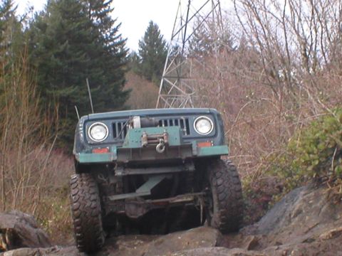 1978 Ford Bronco - Off-road vehicle navigating a rocky path, equipped with a front winch. Likely a 1978 Ford Bronco.