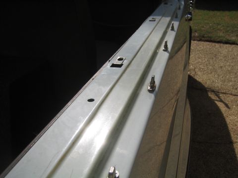 1996 Ford Bronco - Sunlit close-up along a white body tub rail with the soft top removed, showing the bare bedside lip fitted with chrome lift-the-dot studs a…
