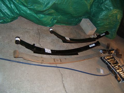1988 Ford Bronco - Several leaf springs are laid out on a concrete floor, some with price tags and part numbers visible.