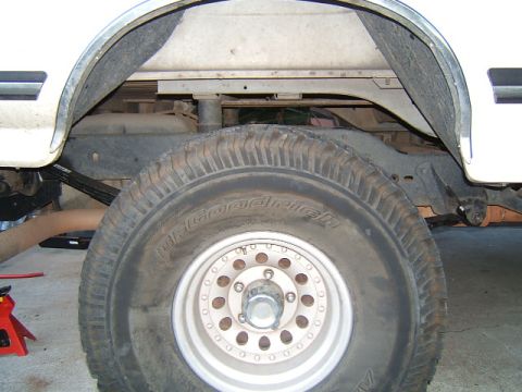 1988 Ford Bronco - The rear suspension of a vehicle, showing the leaf springs and tire, is visible in this close-up shot.