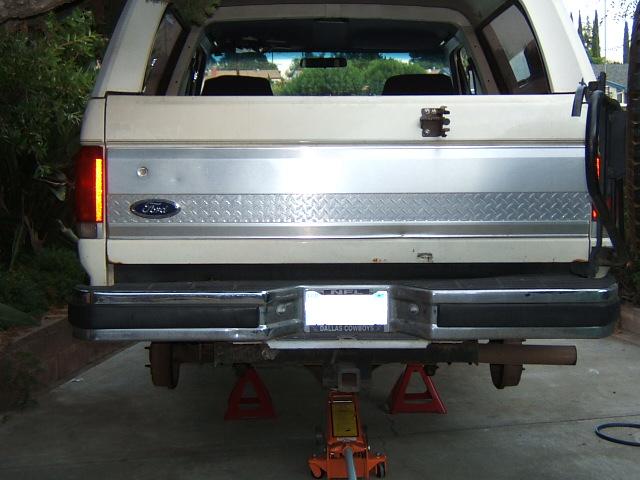 1988 Ford Bronco rear view, lifted on jack stands with a floor jack under the hitch