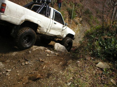1978 Ford Bronco - White pickup truck with off-road tires navigating a rocky, dirt incline.