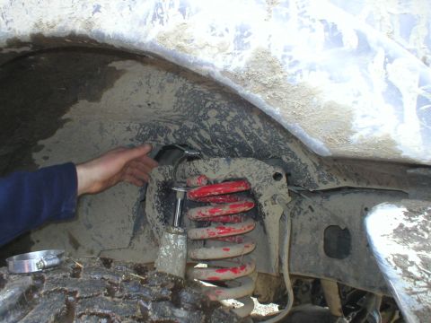 1978 Ford Bronco - A person's hand is visible near the suspension components and tire of a dirty vehicle.