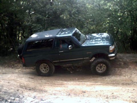 1996 Ford Bronco - This 1996 Ford Bronco is seen off-road on a dirt path surrounded by trees.