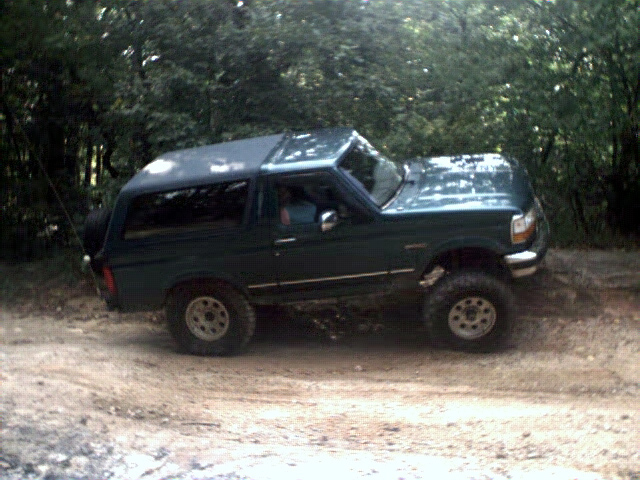 Dark green 1996 Ford Bronco on a dirt road with a spare tire on the back
