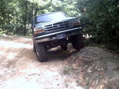 1996 Ford Bronco - This Ford Bronco is navigating a rocky obstacle on a wooded trail.